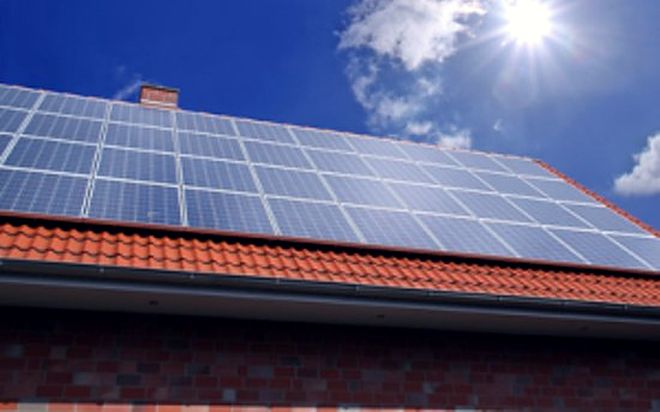 Einfamilienhaus mit Solaranlage auf dem Ziegeldach bei Sonnenschein